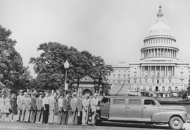 Photo of workers lined up in front of Capitol waiting for a ride in an extended length car.