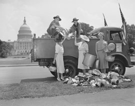 Photo of several three women and two boys loading tin-ware into a truck in front of the Capitol Building.