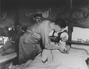 Photo of Senator Lodge pinning Purple Heart on wounded soldier.