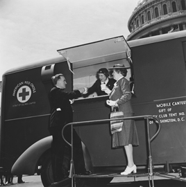 Photo of a Red Cross worker serving coffee to a man and woman from a truck in front of the Capitol Building.